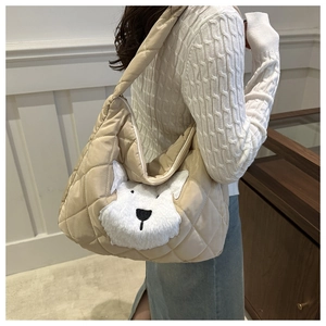 Close-up of beige quilted tote bag with a cute white puppy plush patch detail