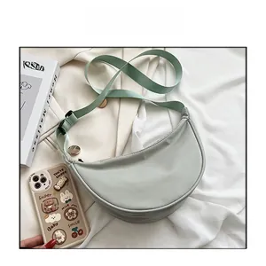 Detail of mint green crescent nylon bag with adjustable fabric strap and metal hardware