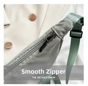 Macro detail of the smooth black metal zipper on the mint green nylon crescent bag