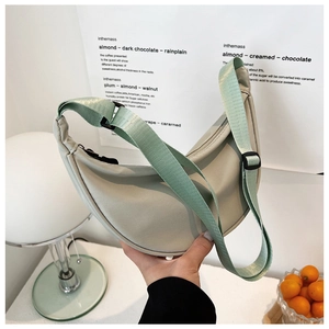 Close-up of a light green nylon crescent bag with adjustable strap in home setting