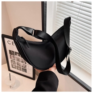Detail of minimalist black nylon crescent bag with adjustable wide fabric shoulder strap