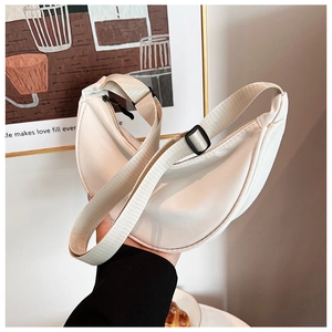 Detail of a creamy beige nylon crescent bag with adjustable wide strap and black buckles