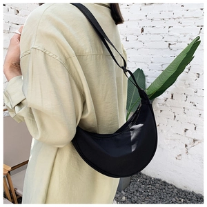 Minimalist black nylon crescent shoulder bag shown in an urban casual lifestyle setting
