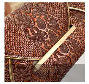 Macro shot of dark brown embossed crocodile leather with golden metal trim details