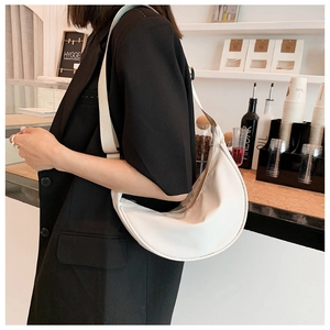 Detailed side view of a white nylon crescent bag worn over a casual black outfit