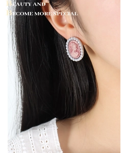 Macro shot of pink cameo earrings with faux pearls on a model for an elegant retro look
