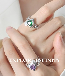 Close-up of chain-style rings with green and purple heart crystals in silver finish