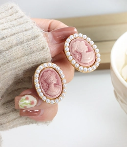 Close-up of vintage cameo earrings with pink lady profile and white pearl border