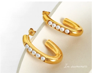 Close-up of gold-plated U-shaped hoop earrings with five inlaid white pearls