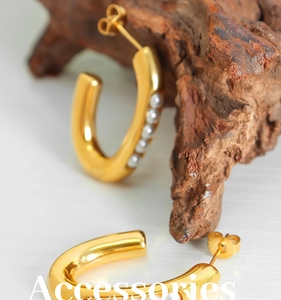 Detailed macro view of gold-plated U-shaped hoop earrings featuring four inlaid pearls