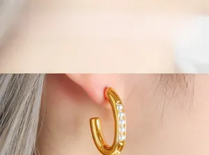 Close-up of C-shaped gold-plated titanium earrings with five white pearls on model