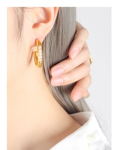 Close-up of gold U-shaped earrings with five inlaid white pearls on model's ear