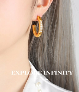 Close-up of elegant gold C-shaped earrings with pearls worn by a model in profile
