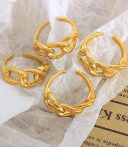 Detail of four 18K gold plated chain link rings on a white textured background