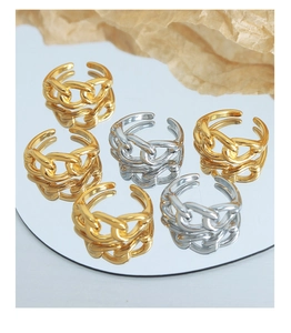 Close-up of gold and silver Cuban chain link rings displayed on a reflective mirror surface