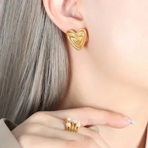 18K gold plated heart stud earrings with concentric circle texture on a female model