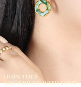 Close-up of 18K gold earrings and ring set with green resin and white pearls