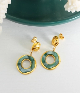 Detail of 18K gold earrings with green resin circles and sparkling rhinestones