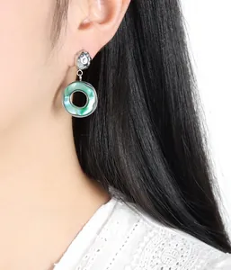 Detail of drop earrings featuring green shell rings and textured silver metallic discs