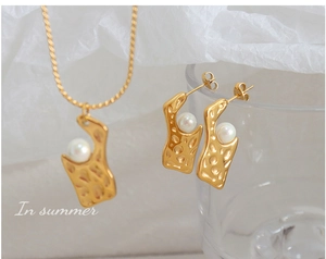 Détail d'un ensemble de bijoux en métal martelé doré avec perles blanches