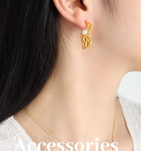 Détail d'un ensemble de bijoux dorés à texture irrégulière et détails de perles