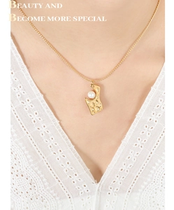 Détail d'un collier doré martelé avec une perle blanche sur un col en dentelle