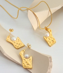 Vue détaillée d'une parure de bijoux dorés martelés avec collier et boucles d'oreilles perles