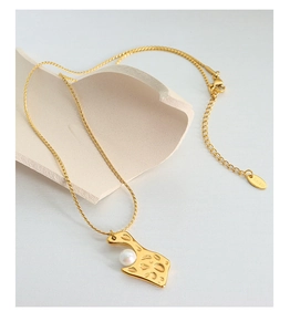 Détail du pendentif doré martelé avec perle blanche et étiquette gravée S.Steel