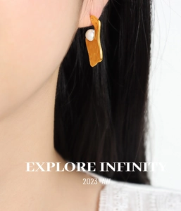 Gros plan sur boucles d'oreilles dorées ondulées avec perle sur l'oreille du mannequin