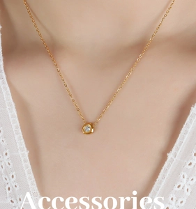 Close-up of a gold O-chain necklace featuring a meteorite-shaped zircon pendant on model