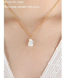 Nahaufnahme der eleganten Goldkette mit weißem Hasenanhänger am Hals des Modells