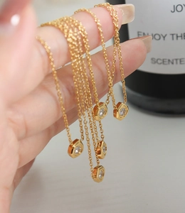 Detailed close-up of gold chain necklaces featuring hexagonal zircon pendants on fingers