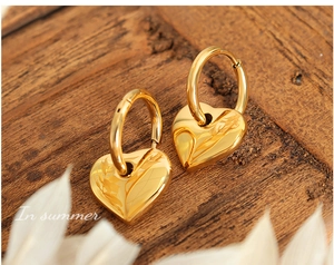 Dettaglio di orecchini a cuore in oro 18 carati su superficie di legno dal look vintage