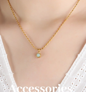 Gros plan d'un collier de perles dorées avec pendentif rond en pierre bleue sur mannequin