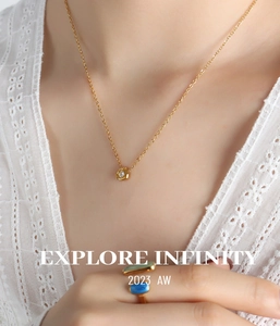 Detailed shot of gold pendant necklace with zircon and emerald-cut multi-color gem ring