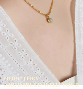 Gros plan d'un collier à perles plaqué or avec une pierre turquoise sur dentelle blanche