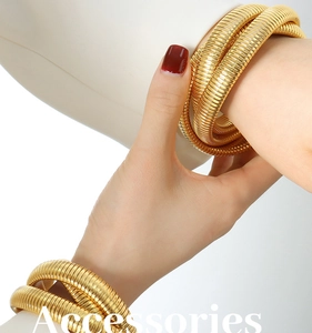 Detail of gold-plated triple-layered snake coil bracelet worn on a female wrist
