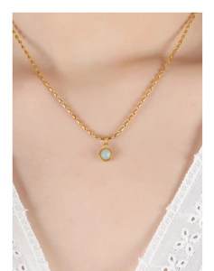 Détail d'un collier plaqué or vintage avec pendentif en pierre bleue sur col en dentelle