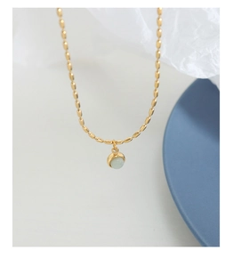 Détail d'un collier chaîne à billes plaqué or vintage avec pendentif en pierre verte
