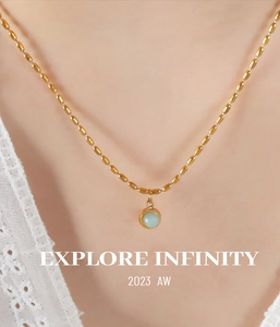 Détail d'un collier de perles dorées vintage avec un pendentif en pierre bleue translucide
