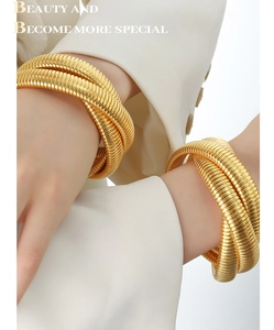 Detail of gold-plated triple snake bone texture cuff bracelet on model sleeve