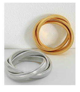 Detailed view of layered gold and silver snake texture bracelets on a white surface