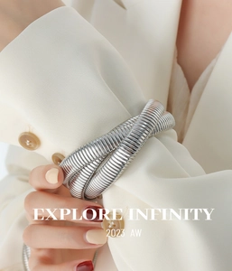 Macro detail of a silver snake textured triple-layer coil bracelet on a white suit cuff