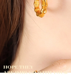 Detail of 18K gold-plated C-shaped earrings with unique lava-like textured metal surface