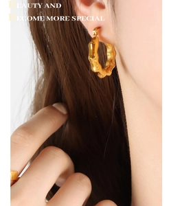 Macro view of gold-plated geometric C-shaped hoop earrings with retro wavy texture