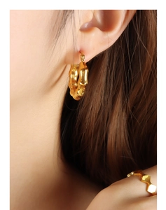 Detail of 18K gold-plated C-shaped earrings and ring with bamboo texture on a model