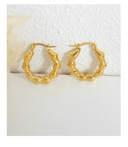 Macro detail of gold-plated bamboo texture hoop earrings with polished mirror finish