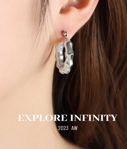 Macro shot of silver C-shaped bamboo texture hoop earring on model with metallic gloss
