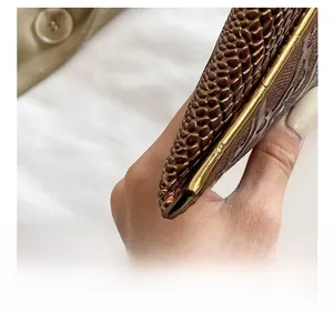 Detail shot of brown crocodile embossed clutch with elegant gold metal frame and texture