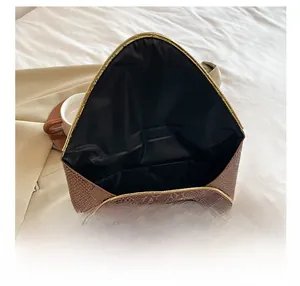 Detail show of the brown snake pattern envelope clutch bag with gold trim and interior space